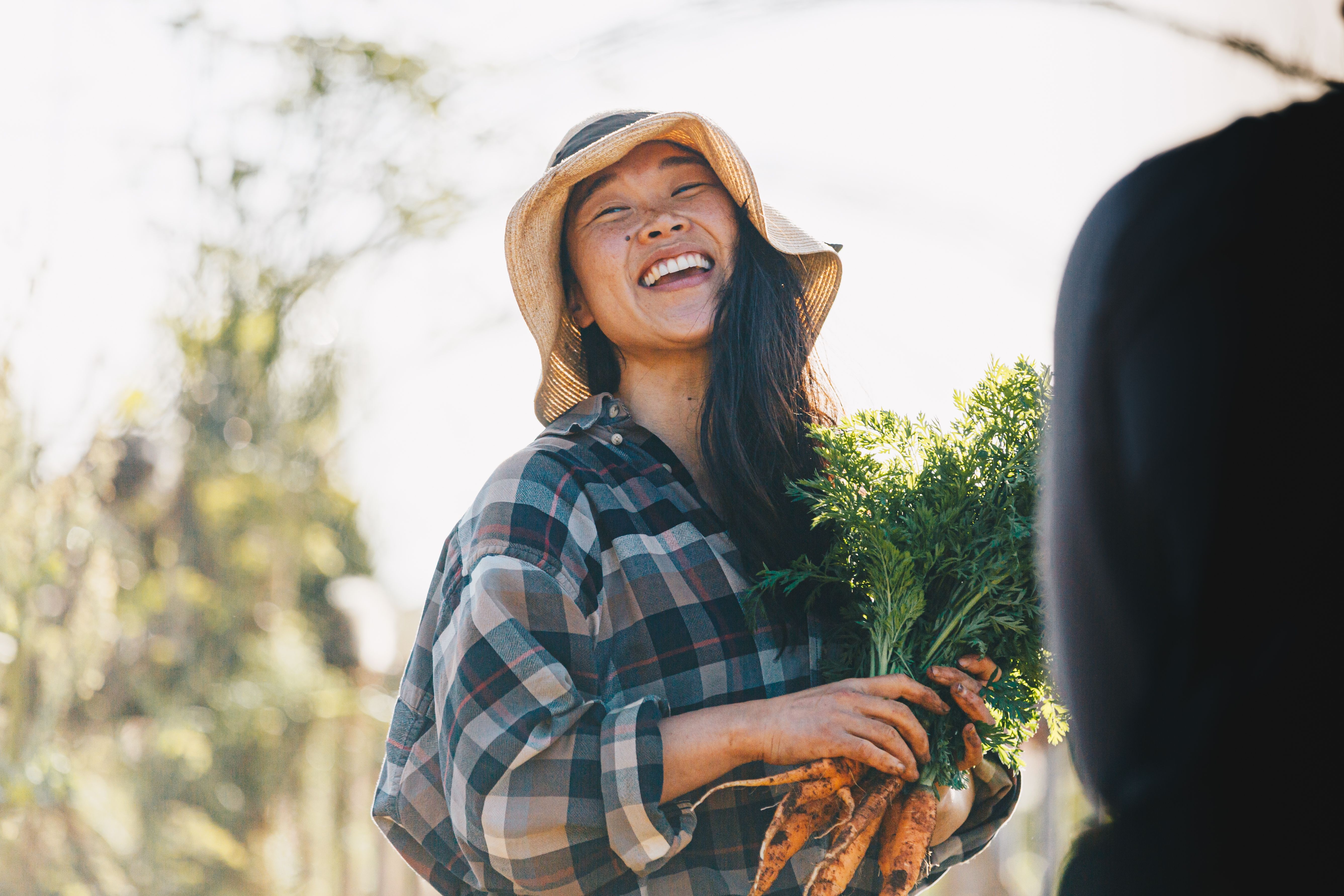 Woman farmer laughing with fresh carrots
